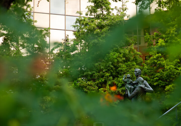 View of the McCombs family statue through leaves.