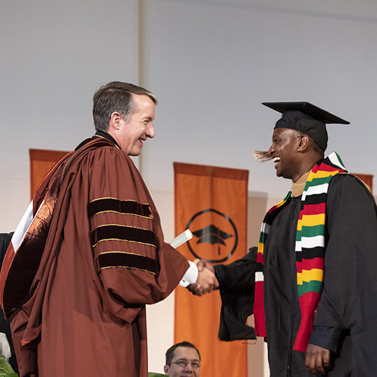 Jay Hartzell shaking hands with graduate