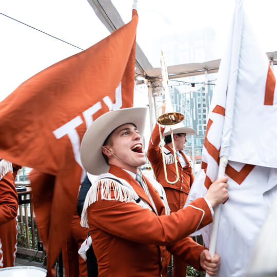 University of Texas band member cheering and holding flag