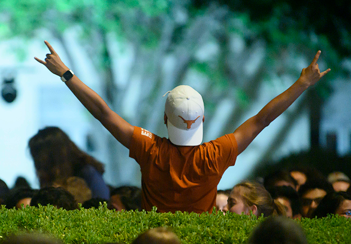back of student who has their arms extended holding up a hook 'em