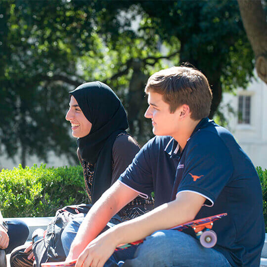 Three students sit talking outside