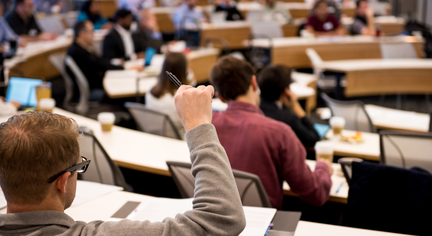 Executive student in large classroom raising hand
