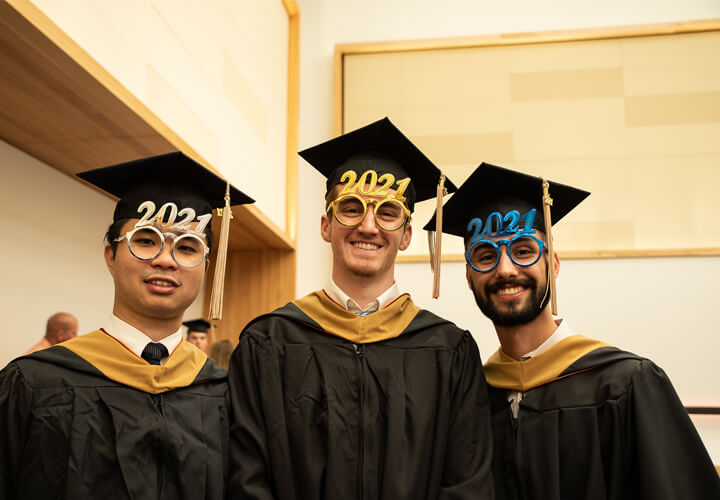 Three smiling graduates in caps and gowns