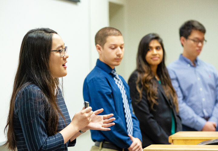 Four students speaking at front of healthcare class