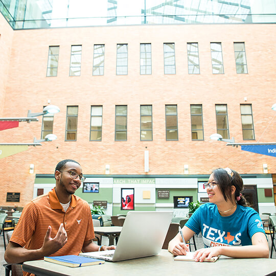 Two students talk in CBA atrium