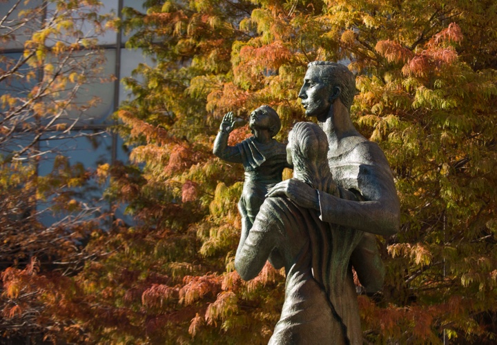 Artistic statue in front of fall trees.
