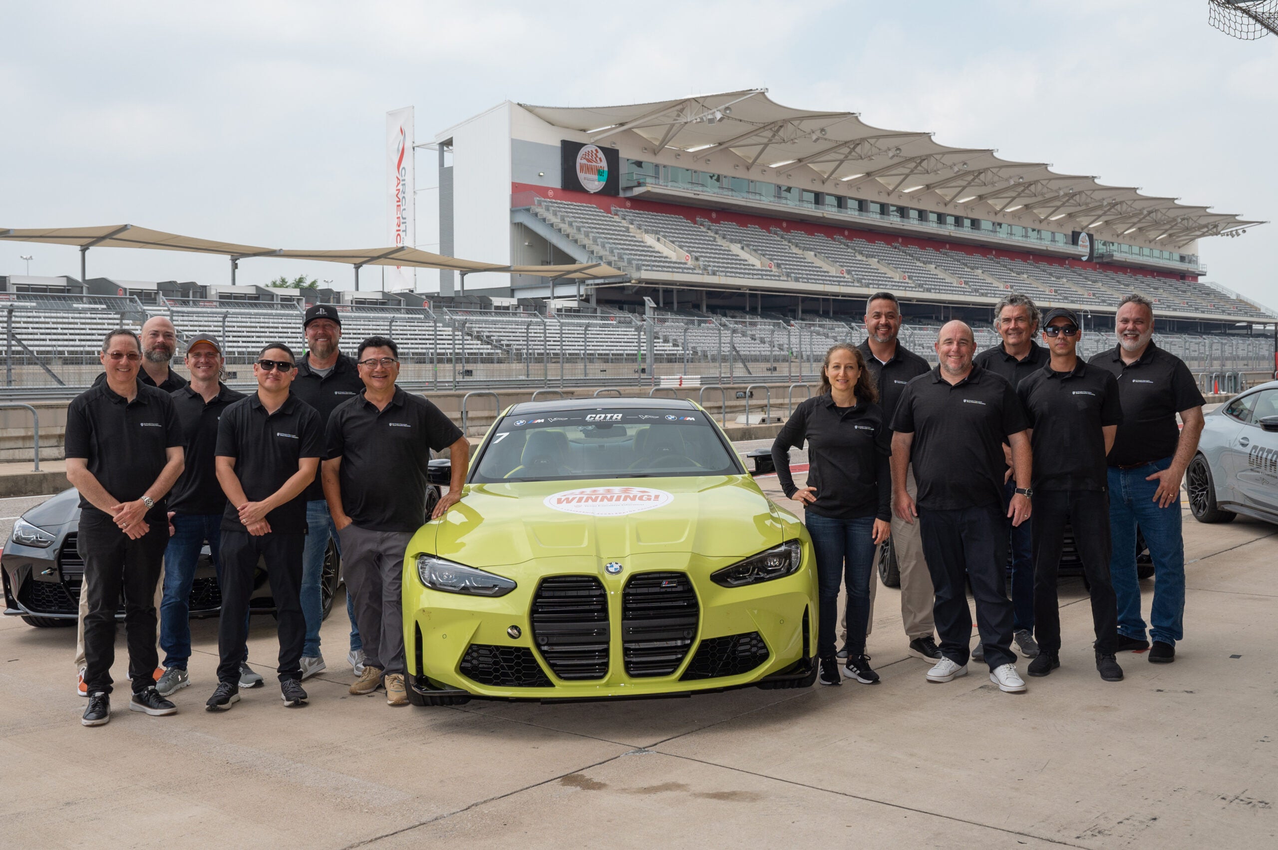 Group of people standing with a race car
